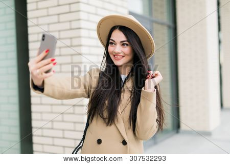 Outdoors Lifestyle Fashion Portrait Of Pretty Young Woman Making Selfie By The Phone. Smiling, Walki