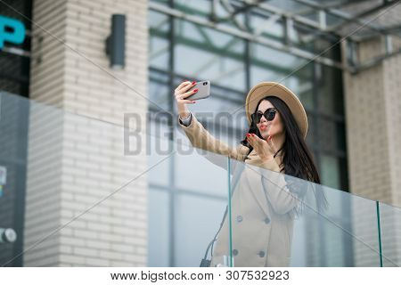 Outdoors Lifestyle Fashion Portrait Of Pretty Young Woman Making Selfie By The Phone. Smiling, Walki