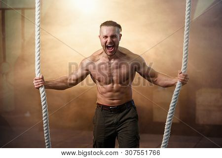 Strong Young Man Screaming While Making Exercise With Crossfit Rope.