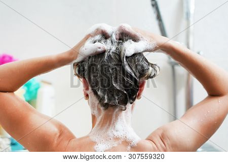 Woman Washing Her Hair With A Lot Of Foam Inside A Shower. Back View Of Young Woman Washing Her Hair