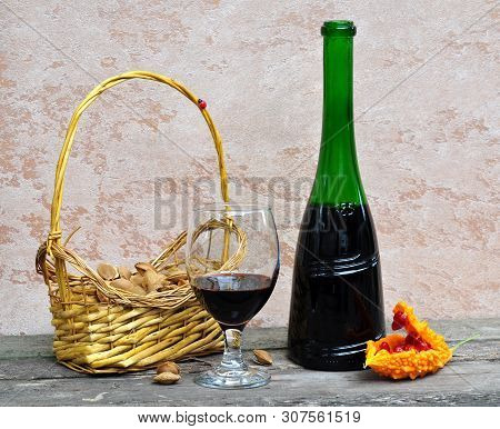 Still Life With Orange Momordika, Wine In A Glass And A Bottle, As Well As A Basket Of Apricot Seeds