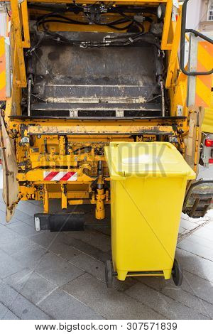 Trash Can Attached To Garbage Truck For Dump Removal In Urban Street