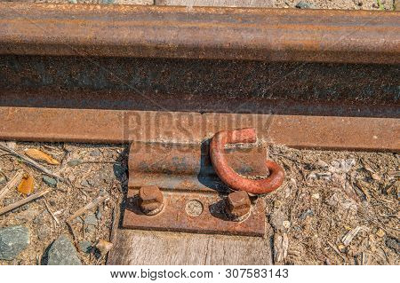 Rusty Old Train Track Rail Bolted Down With A Plate And Bolts To A Wooden Tie