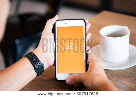Chiang Mai / Thailand - June 22 2019 : Hands Holding Mobile With Alibaba Screen In Coffee Shop.