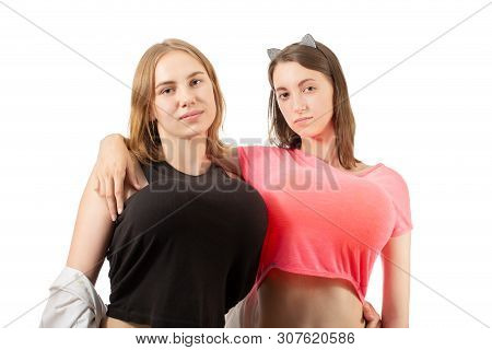 Two Young Women Shows Big Fake Breasts Isolated On White Background Looking At Camera