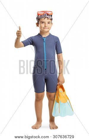 Full length portrait of a young boy in a wetsuit holding swmming fins and showing thumb up isolated on white background