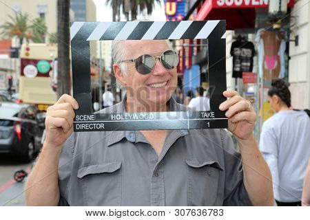 6-18-2019 Hollywood, California: A man wears silver reflective sunglasses while posing with a Hollywood Movie Click Board while on the streets on Hollywood California. Editorial Use Only. 