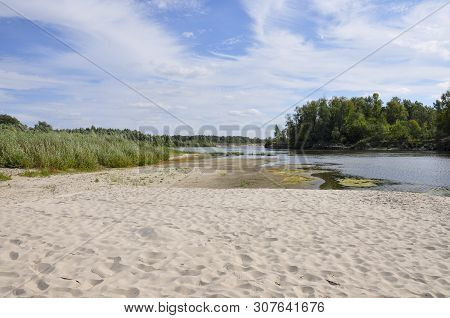 Wide Blue River Is Slow Flowing. Summer. Sunny Weather And White Sand. Green Trees Far Away