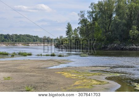 Wide Blue River Is Slow Flowing. Summer. Sunny Weather And White Sand. Green Trees Far Away
