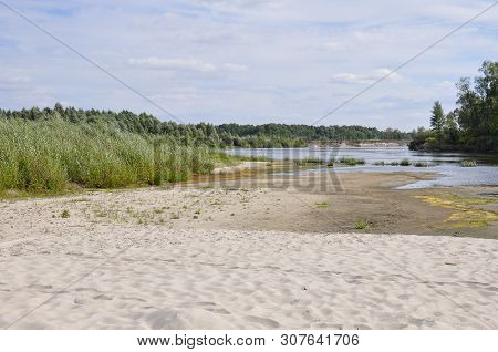 Wide Blue River Is Slow Flowing. Summer. Sunny Weather And White Sand. Green Trees Far Away