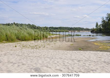 Wide Blue River Is Slow Flowing. Summer. Sunny Weather And White Sand. Green Trees Far Away