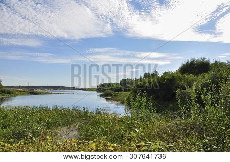 Wide Blue River Is Slow Flowing. Summer. Sunny Weather And White Sand. Green Trees Far Away
