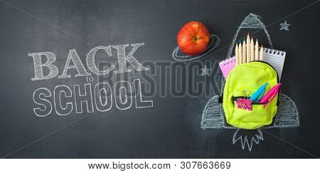 Back To School Concept With Small Bag Backpack, School Supplies And Rocket Sketch Over Chalkboad Bac
