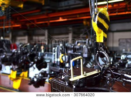 Bridge Lifting Crane Hook Against The Background Of The Assembly Line Industrial Factory. The Concep