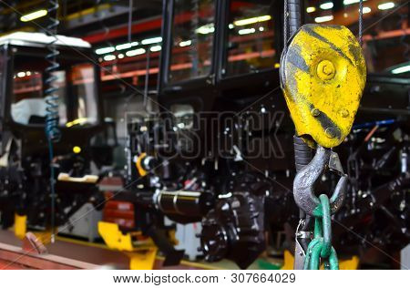 Bridge Lifting Crane Hook Against The Background Of The Assembly Line Industrial Factory. The Concep