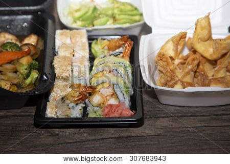Sushi, Wontons And Sliced Avocado In Carryout Boxes