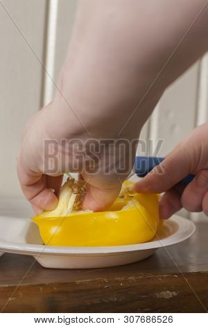 Woman Cutting A Yellow Bell Pepper On A Styrofoam Plate