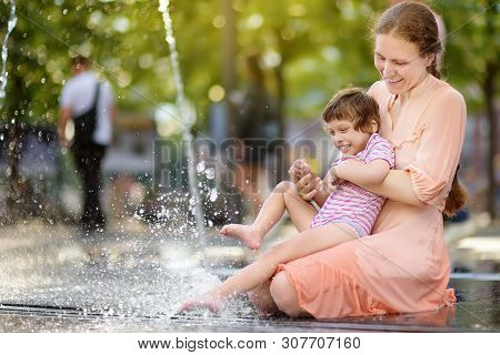 Portrait Of Beautiful Disabled Girl In The Arms Of His Mother Having Fun In Fountain Of Public Park 