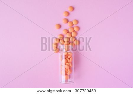 Orange Tablets From Glass Bottle On Pink Background. Copyspace For Text. Epidemic, Painkillers, Heal