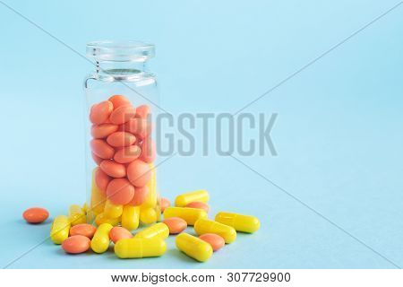 Yellow And Orange Capsules From Glass Bottle On Blue Background. Copyspace For Text. Epidemic, Paink