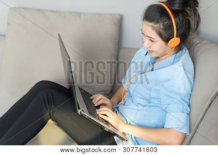Young Woman Sitting On Sofa With Laptop And Headphones Enjoy Favorite Song. Girl Listening Music Wit
