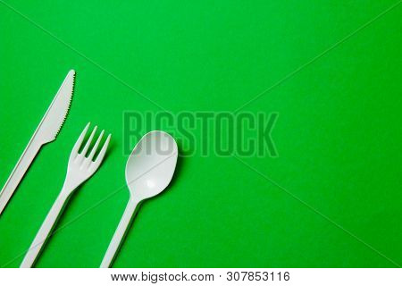 White Single-use Plastic Knives, Spoons, Forks On A Green Background. Say No To Single Use Plastic. 