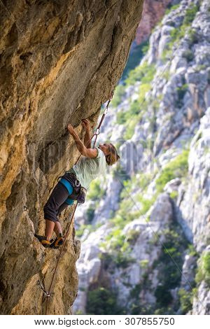 Rock Climbing And Mountaineering In The Paklenica National Park. A Woman Overcomes A Challenging Cli