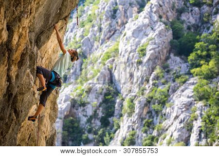 Rock Climbing And Mountaineering In The Paklenica National Park. A Woman Overcomes A Challenging Cli