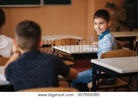 Cute Boy Lool Arround In Class Room. Back View Of Boys