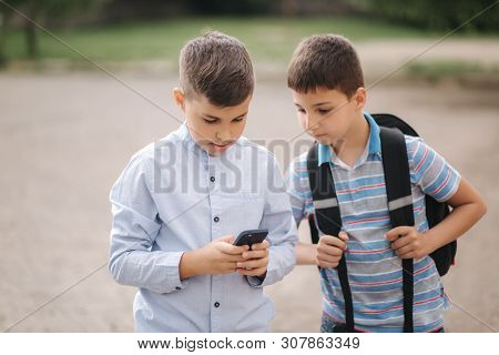 Two Boys Plays Online Games After School Classes. Young Boys Smile And Use Phone