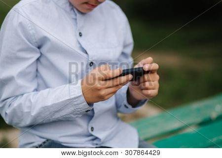Young Boy Sitting On The Bench And Play Online Games During School Break