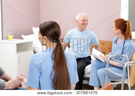 Nurses With Senior Patients In Hospital Ward. Medical Assisting