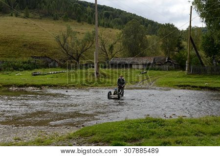 Altai Region, Russia - September 4, 2018: Local Residents Wade Through A Mountain River Yarivka In T