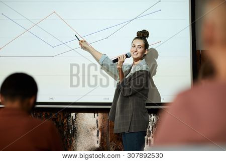 Waist Up Portrait Of Contemporary Businesswoman Giving Presentation Pointing At Graph Lines On Proje