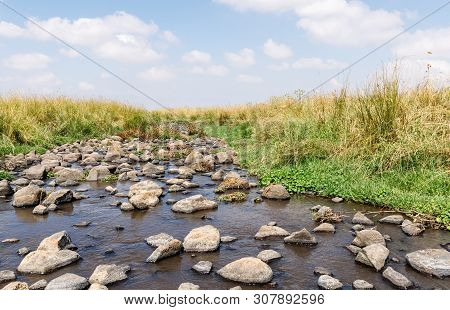 Shallow River Flowing Near The Remnants Of The Early Bronze Age Megalithic Complex Of The Early Bron