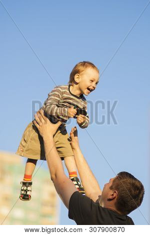 Father And Son Having Fun Together Outdoors.dad Tossing Son Up Against Blue Sky.  Vertcal Compositio