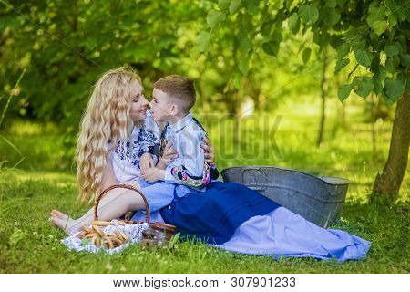 Portrait Of Happy Caucasian Mother Kissing Her Little Kid. Posing With Basket Full Of Bread Rings Ou