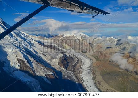Aerial View Of Alaska Mountaion Range Around Denali Peak From A Plane With Glaciers Around And Blue 