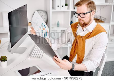 Mid Age Businessman Working With Dokuments At The Computer In Office