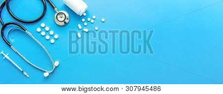 Pills And Medical Equiupments Including Stethoscope, Syringe At Border On Light Blue Background, Pan
