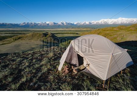 Tourist Warms His Feet In The Morning Sun. Panorama Of The Snow Capped Mountains In Altai Republic, 