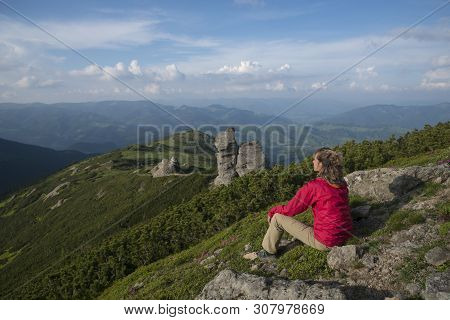 Woman Dressed In Red Jacket Contemplates Summer Landscape In Mountains.