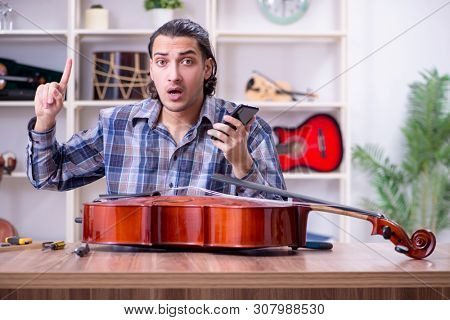 Young handsome repairman repairing cello