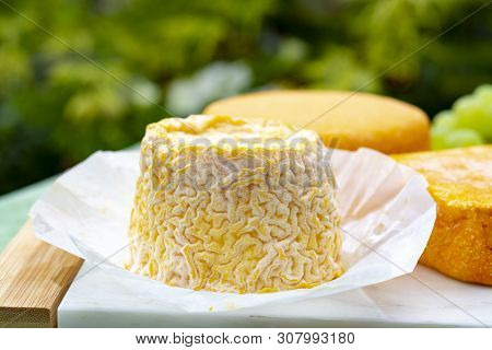 French Cheeses Collection, Langres And Le Peche Des Bons Peres Cheeses Served With Grapes On White M