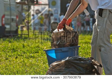 Blue Litter On Green Grass. Garbage In The Nature After The Concert. The Cleaner Changes Garbage Bag