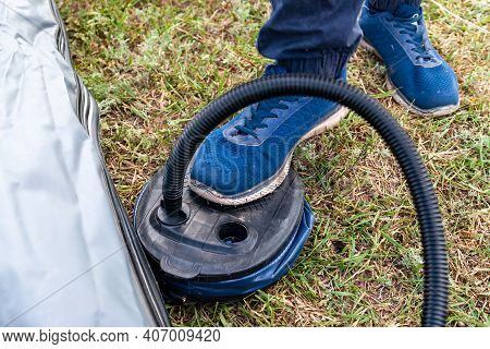 Inflatable Boat Pumping Process, Close-up. A Fisherman Pumps An Inflatable Boat With A Foot Pump.