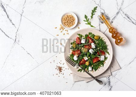Healthy Vegetarian Salad With Fresh Arugula, Cherry Tomatoes, Soft Cheese, Olives And Pine Nuts
