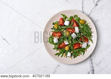 Healthy Vegetarian Salad With Fresh Arugula, Cherry Tomatoes, Soft Cheese, Olives And Pine Nuts