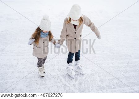 Beautiful Little Girls, Sisters Learn To Skate On Ice Skating Rink In Park. Fall And Have Fun. Styli