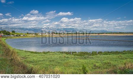 Phishing Ponds Or Lake And Small Industrial Estate In Nin With Beautiful Mountain Range Of Dinaric A